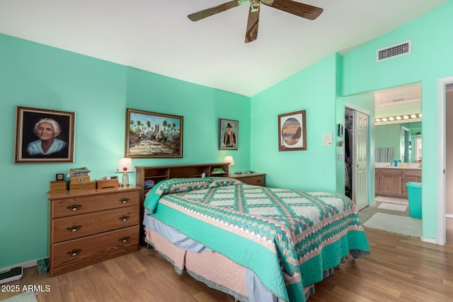 bedroom with vaulted ceiling, ceiling fan, light hardwood / wood-style floors, and ensuite bath