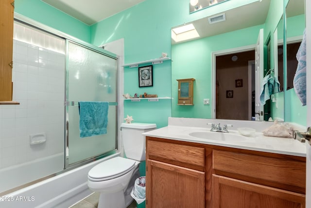 full bathroom with a skylight, vanity, toilet, and bath / shower combo with glass door