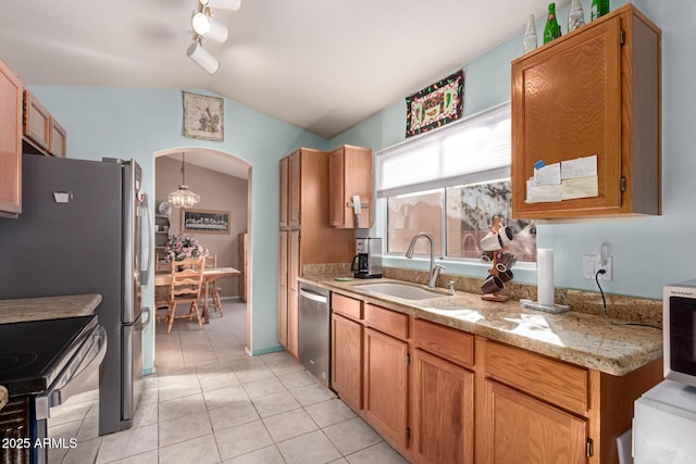 kitchen featuring lofted ceiling, sink, light stone counters, light tile patterned floors, and stainless steel appliances