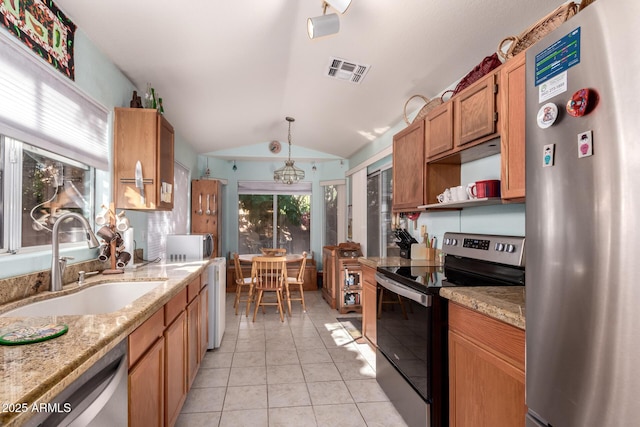 kitchen with lofted ceiling, sink, hanging light fixtures, light tile patterned floors, and stainless steel appliances