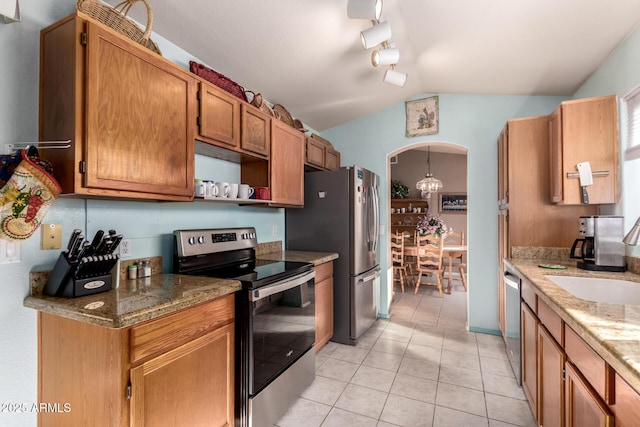 kitchen with lofted ceiling, sink, light tile patterned floors, appliances with stainless steel finishes, and light stone countertops