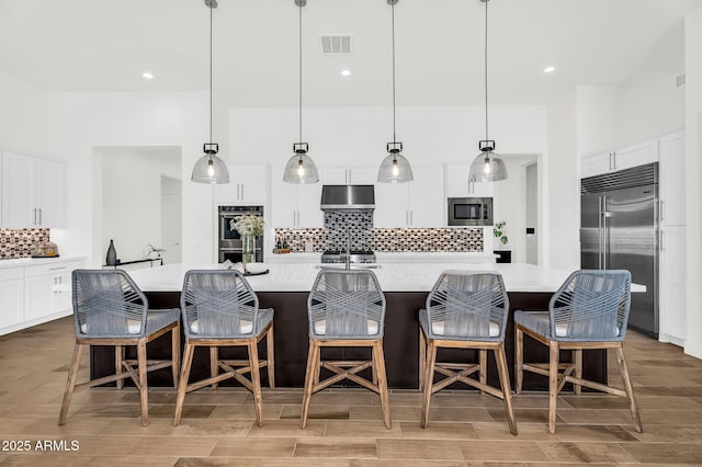 20716 E Pummelos Rd, Queen Creek, AZ 85142 - kitchen featuring built in appliances, under cabinet range hood, tasteful backsplash, light countertops, and a spacious island