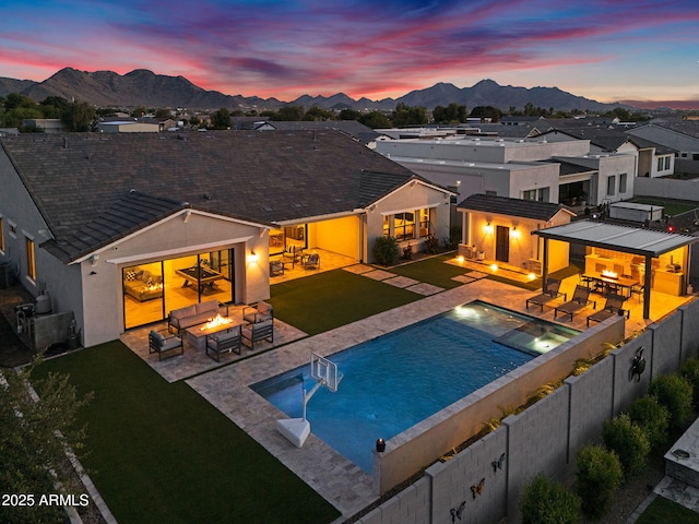 20716 E Pummelos Rd, Queen Creek, AZ 85142 - pool at dusk with a fire pit, a mountain view, a patio area, a fenced backyard, and a pool with connected hot tub