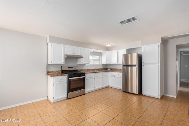 kitchen with white cabinetry, light tile patterned floors, stainless steel appliances, dark stone counters, and sink