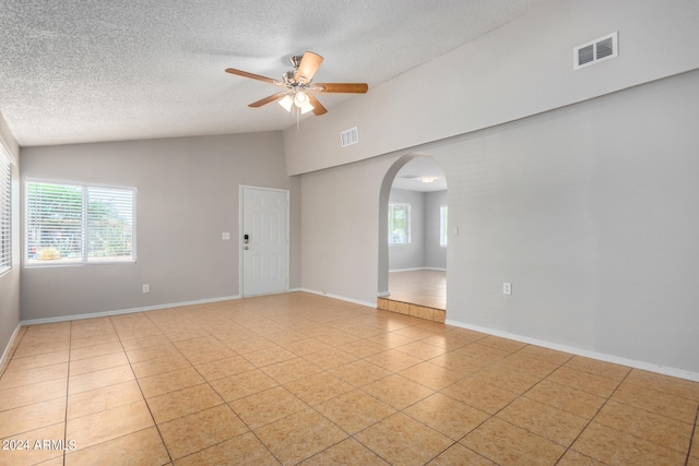 unfurnished room with ceiling fan, light tile patterned flooring, lofted ceiling, and a wealth of natural light