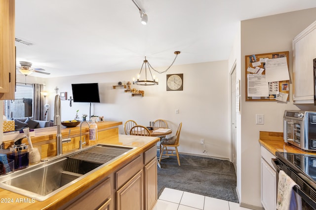 kitchen with pendant lighting, sink, light brown cabinetry, light colored carpet, and ceiling fan with notable chandelier