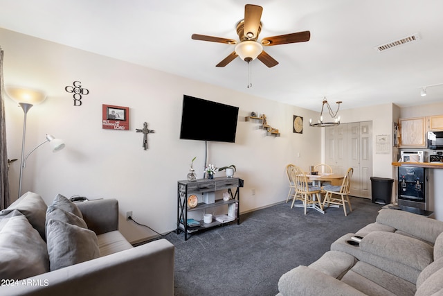 carpeted living room featuring ceiling fan with notable chandelier and beverage cooler