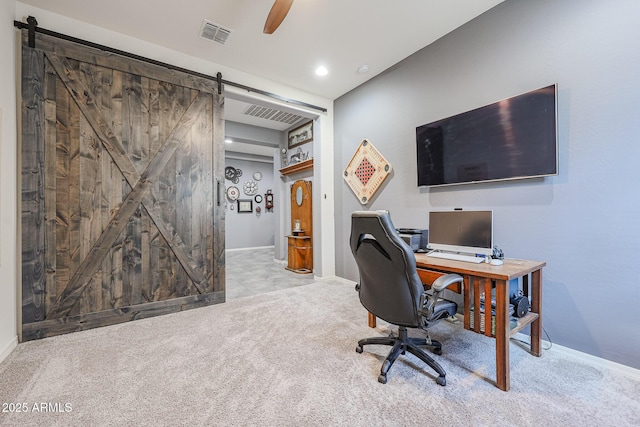 office space with light colored carpet, ceiling fan, and a barn door