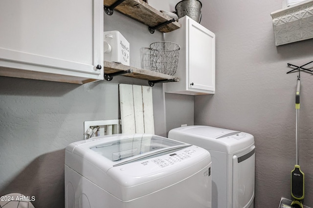 clothes washing area with cabinets and washer and clothes dryer