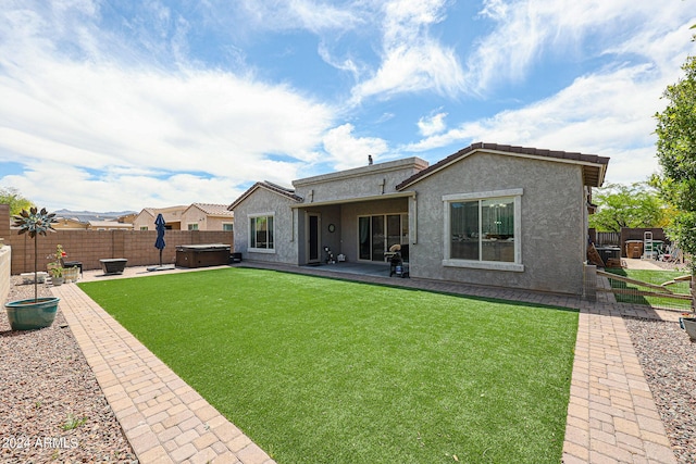 back of property featuring a patio area, a lawn, and a hot tub