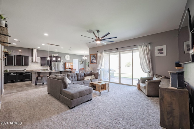 living room featuring ceiling fan with notable chandelier and light colored carpet