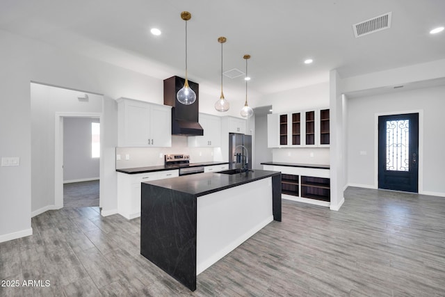 22548 W Huntington Dr, Buckeye, AZ 85326 - kitchen with stainless steel appliances, dark countertops, light wood-type flooring, a center island with sink, and recessed lighting