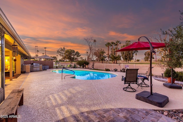 pool at dusk featuring exterior kitchen, a fenced in pool, a patio area, and a fenced backyard