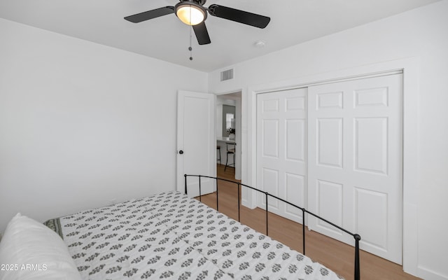 bedroom featuring hardwood / wood-style flooring, ceiling fan, and a closet