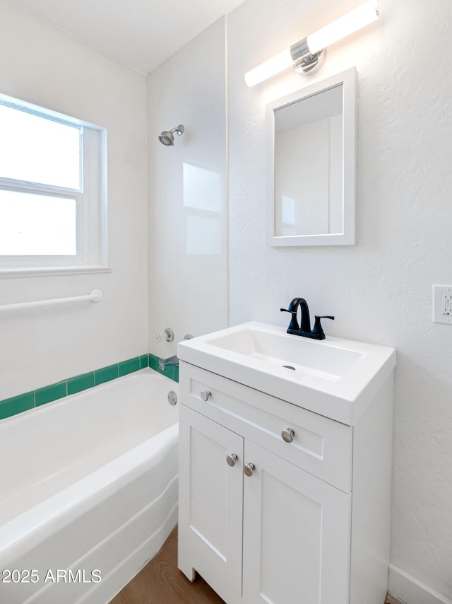 bathroom with hardwood / wood-style flooring, vanity, and a bathtub