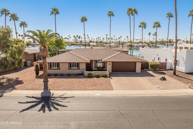 view of front of home featuring a garage, driveway, central AC unit, and a water view