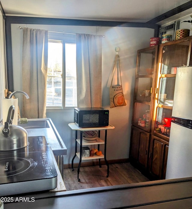 kitchen with black microwave, a sink, and wood finished floors