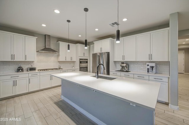 12806 W Mclellan Rd, Glendale, AZ 85307 - kitchen with wall chimney range hood, stainless steel appliances, light wood-type flooring, tasteful backsplash, and recessed lighting
