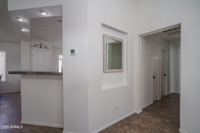 hallway with baseboards, visible vents, and plenty of natural light