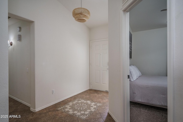 corridor featuring tile patterned floors, baseboards, and high vaulted ceiling