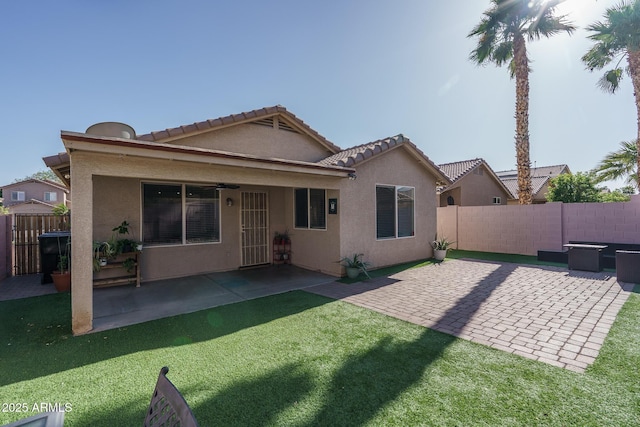 back of property featuring a ceiling fan, a fenced backyard, a yard, a patio, and stucco siding