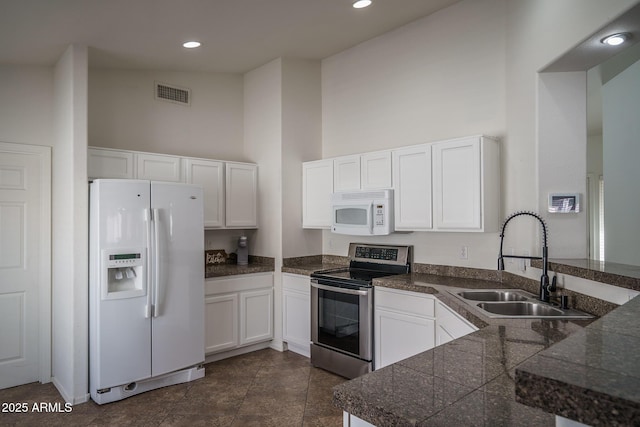 kitchen with tile countertops, a towering ceiling, visible vents, a sink, and white appliances