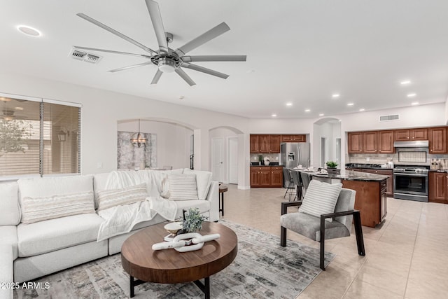 living area featuring arched walkways, light tile patterned floors, recessed lighting, visible vents, and a ceiling fan