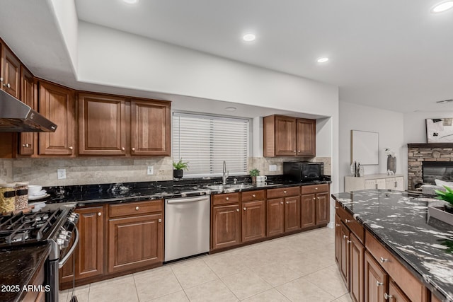 kitchen featuring dark stone counters, stainless steel appliances, tasteful backsplash, and a sink