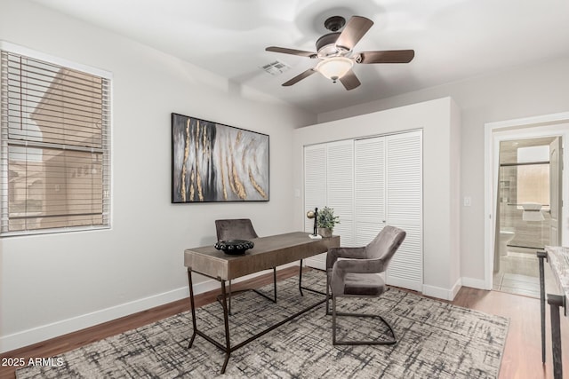 home office with baseboards, visible vents, ceiling fan, and wood finished floors