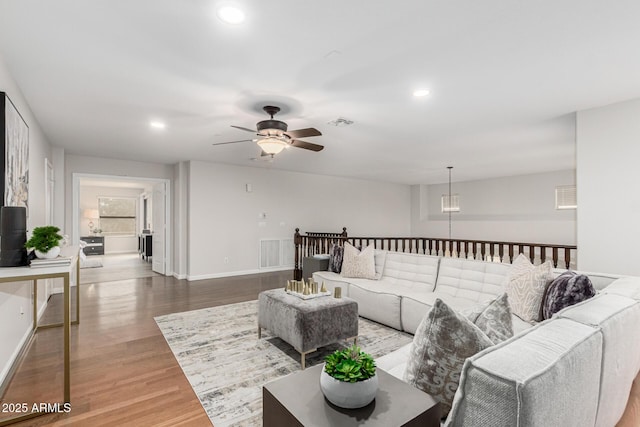 living area with recessed lighting, visible vents, baseboards, and wood finished floors