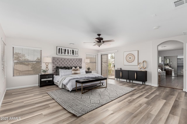 bedroom featuring arched walkways, access to outside, wood finished floors, and visible vents