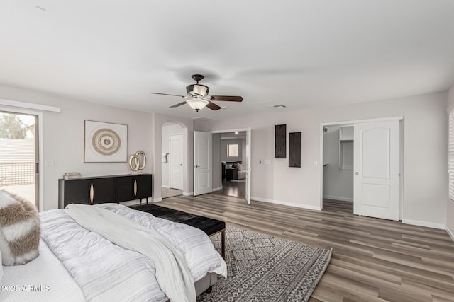 bedroom featuring visible vents, baseboards, a ceiling fan, arched walkways, and wood finished floors