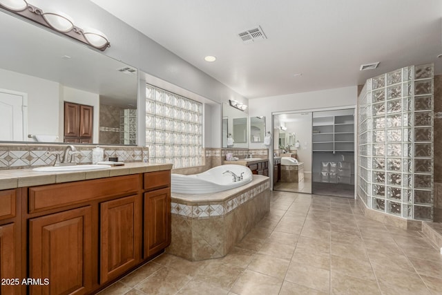 full bath with a bath, tasteful backsplash, a sink, and visible vents