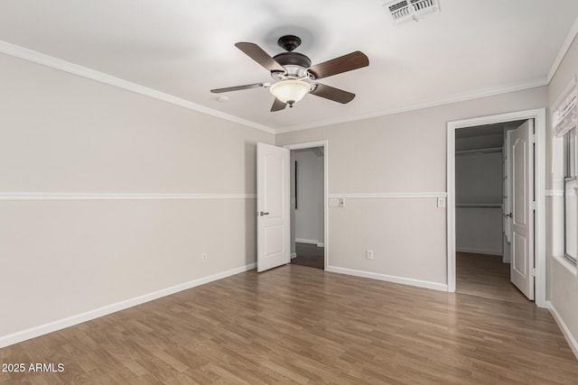 unfurnished bedroom with light wood-style flooring, a spacious closet, visible vents, and ornamental molding