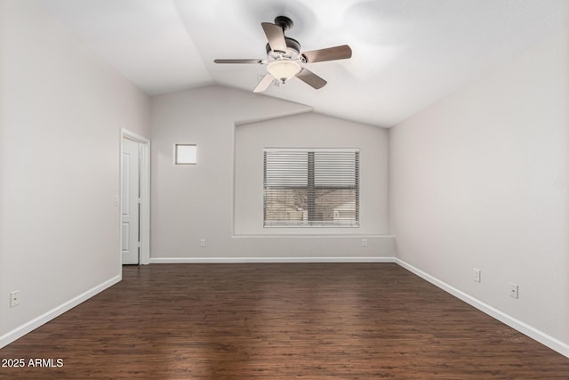 spare room with dark wood-style floors, vaulted ceiling, a ceiling fan, and baseboards