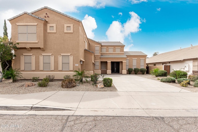 view of front facade featuring driveway, a tiled roof, and stucco siding