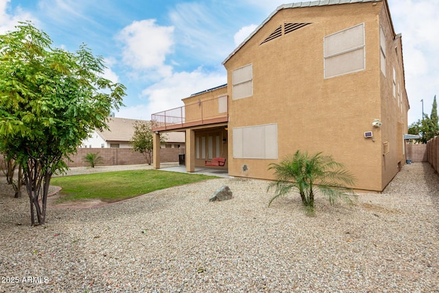 back of house featuring a patio area, a fenced backyard, a balcony, and stucco siding