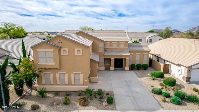 view of front of home with concrete driveway, a tile roof, a residential view, and stucco siding