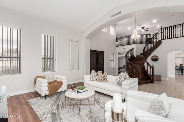 living room with arched walkways, visible vents, stairway, wood finished floors, and baseboards