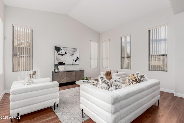 living area featuring lofted ceiling, wood finished floors, and baseboards