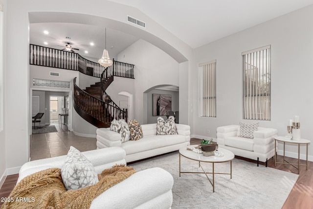 living room with stairway, baseboards, visible vents, and wood finished floors