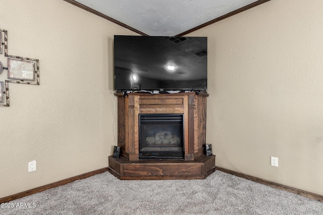 unfurnished living room featuring a glass covered fireplace, baseboards, ornamental molding, and carpet flooring