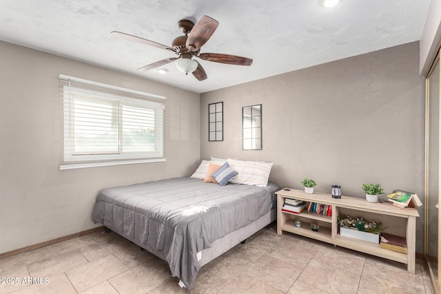 bedroom featuring baseboards, multiple windows, a ceiling fan, and light tile patterned flooring