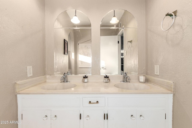 bathroom featuring double vanity, a textured wall, and a sink