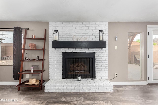 interior details with a brick fireplace, baseboards, and wood finished floors
