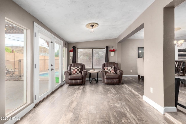sitting room with baseboards, wood finished floors, and vaulted ceiling