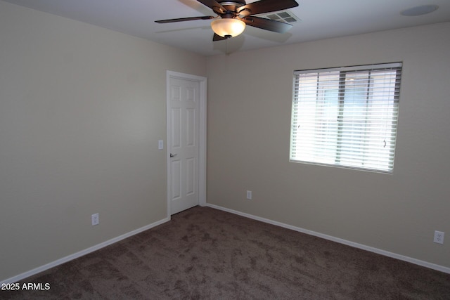 spare room featuring dark carpet and ceiling fan