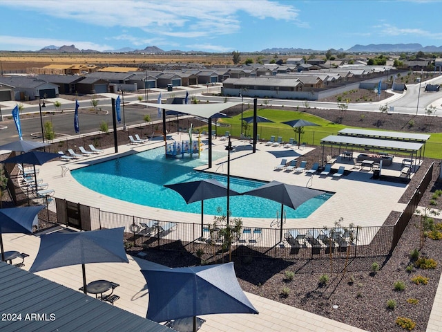 pool featuring a residential view, a patio area, fence, and a mountain view