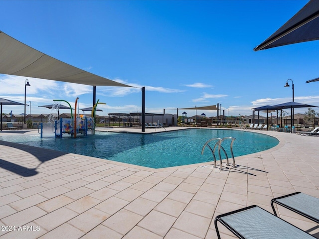 pool featuring a patio, fence, and a water play area