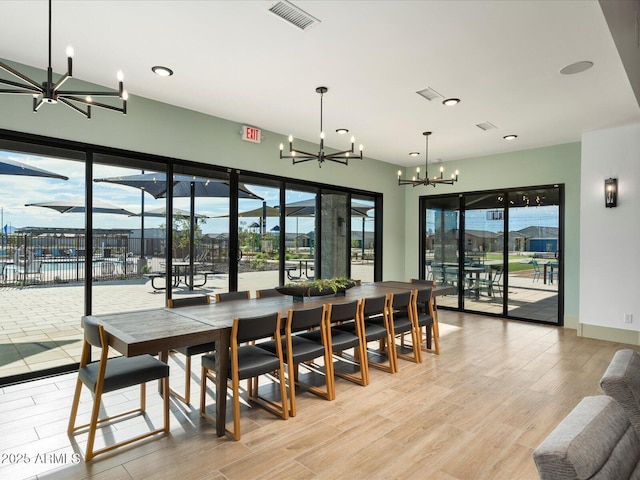 dining space featuring light wood-type flooring, an inviting chandelier, plenty of natural light, and visible vents